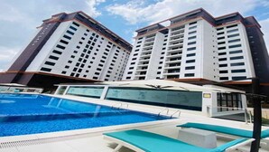 A swimming pool with lounge chairs, surrounded by high-rise buildings. - crestpark apartments (Nairobi)