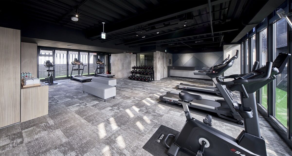 Une salle de sport moderne équipée de tapis de course, de vélos elliptiques et de supports à poids.