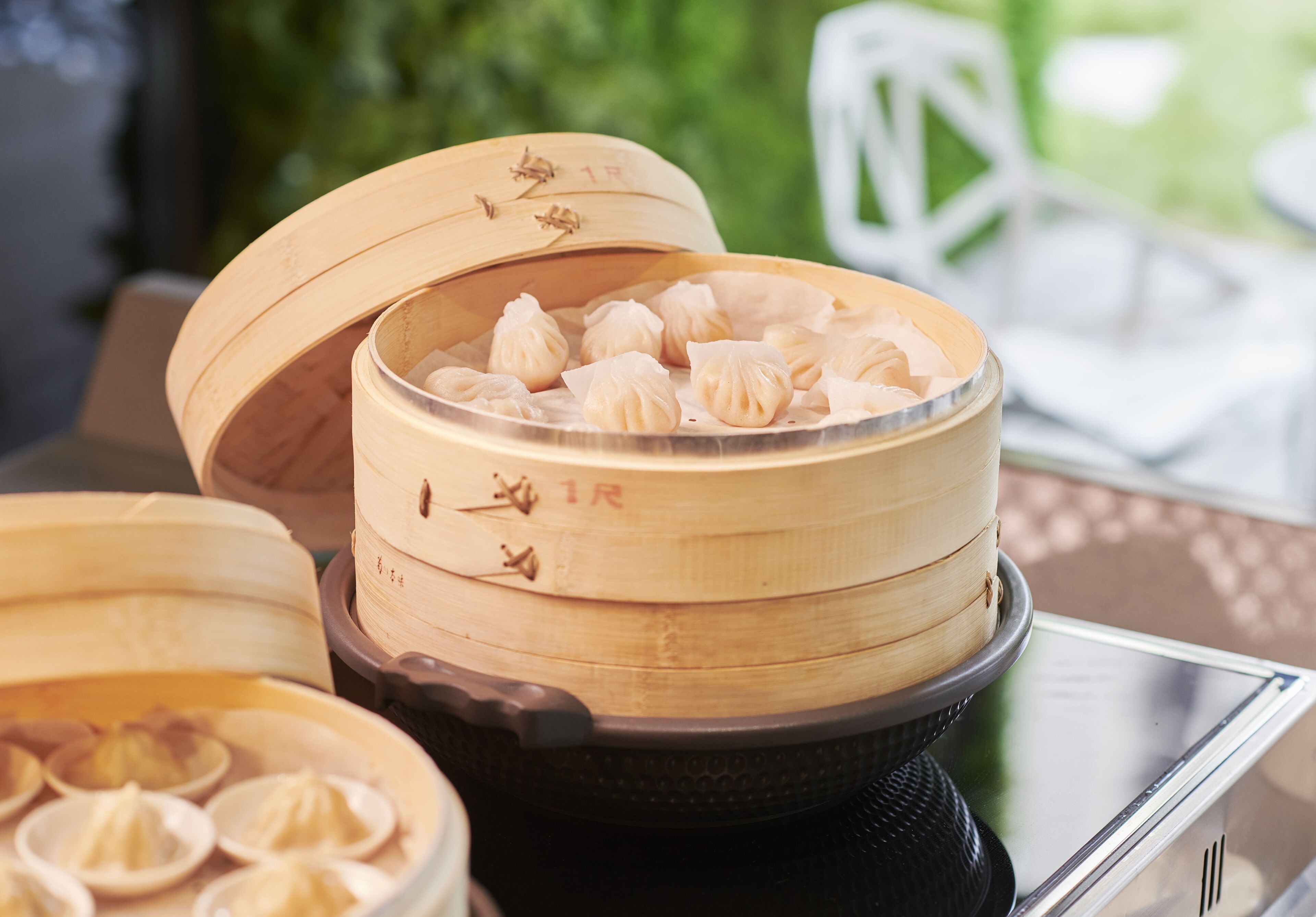 Un panier vapeur en bambou contenant des raviolis, posé sur une table.