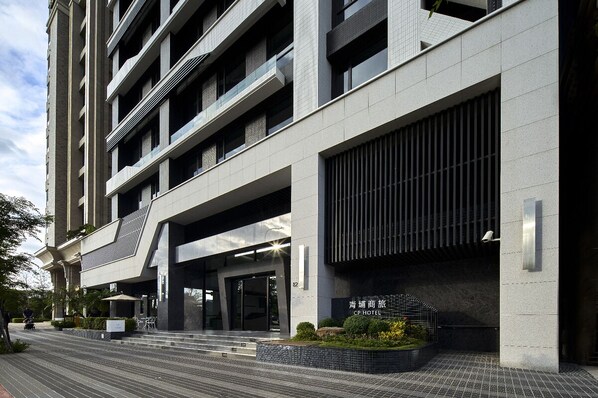 A modern hotel with a clean, minimalist design, featuring a prominent entrance with steps and a covered area.