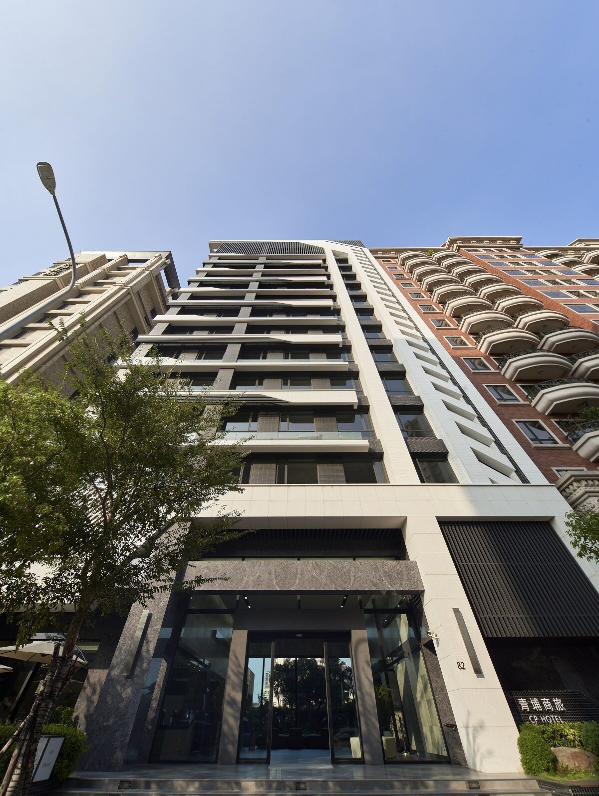 Un moderno edificio de hotel con una entrada destacada, grandes ventanas y cielo despejado.