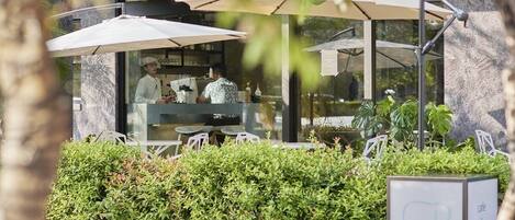 An outdoor cafe with umbrellas, a counter, and seating.