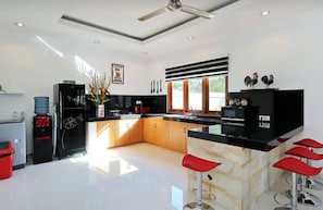 Enjoy cooking in this well-equipped kitchen with a central island, refrigerator, water dispenser, and microwave.