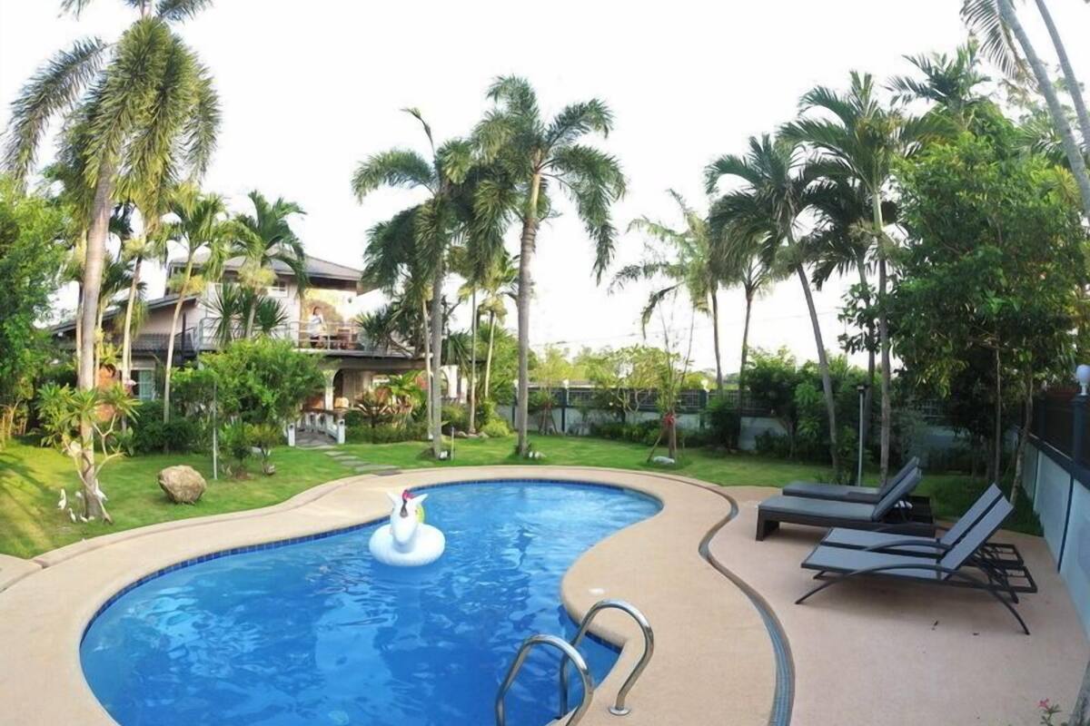 A swimming pool with a small inflatable duck, surrounded by palm trees and lounge chairs.