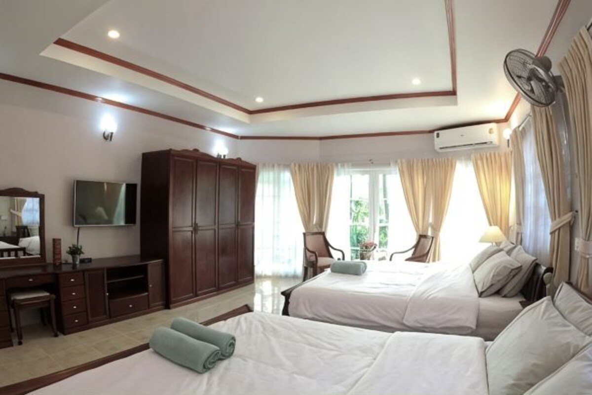 A hotel room with two beds, a TV, a wardrobe, and a desk.