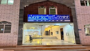 A building with a sign for 'Bait Al Gubaira' offering furnished flats and rooms. - Super OYO 149 Bait Al Ghubaira Furnished Flat (Salalah)