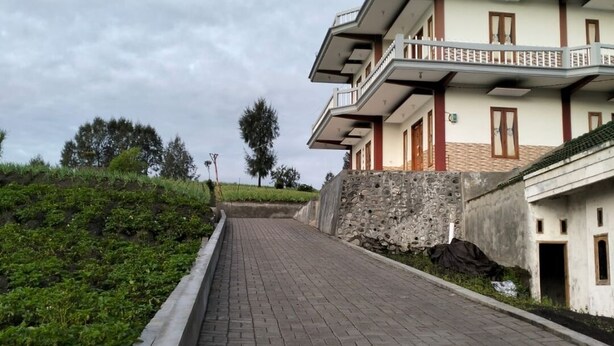 Un camino pavimentado que conduce a un edificio de varios pisos con balcones.