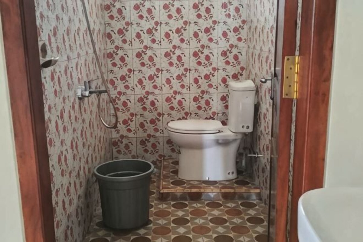 A bathroom with a toilet, bidet, and a trash bin.