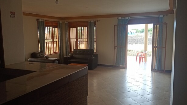 Habitación con mostrador de cocina, dos sofás y puerta corrediza de vidrio que da a un espacio exterior.