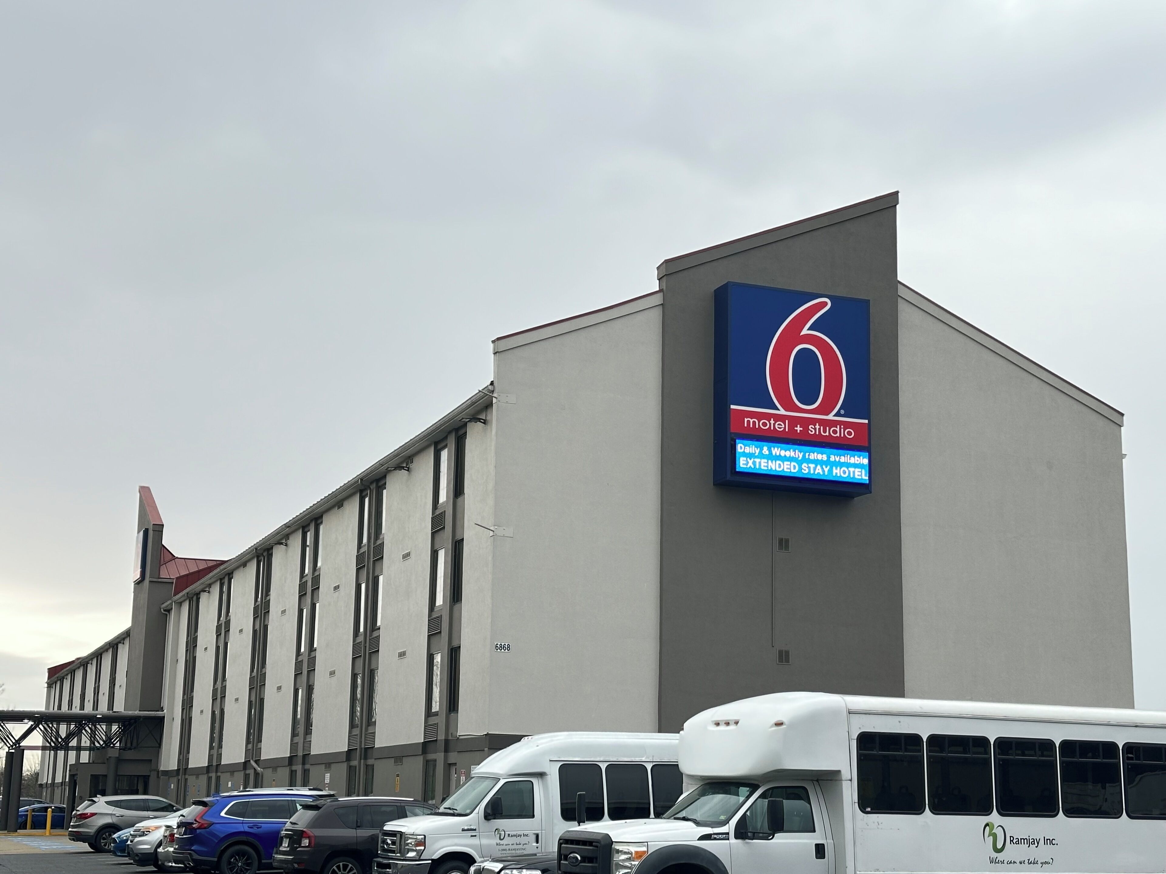A building with a large sign for a motel and studio, parking area, and a bus.