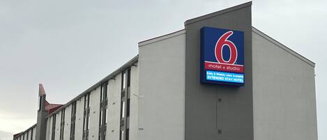 A building with a large sign for a motel and studio, parking area, and a bus.