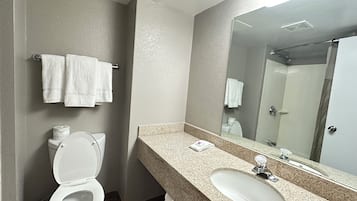 Een bad/douchecombinatie, handdoeken, zeep, toiletpapier
