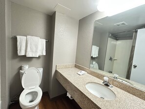 Een bad/douchecombinatie, handdoeken, zeep, toiletpapier