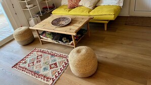A living room with a wooden coffee table, a patterned rug, and two round poufs. - Renovated apartment with beautiful view of the beach golf course 5 minutes away (IB)