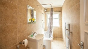 A bathroom with a sink, mirror, shower, and towel rack. - Remarkable Studio Apartment in Central London (London)