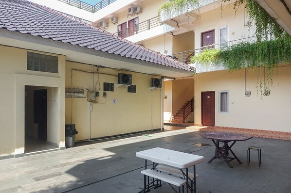Un patio con techo de tejas, una mesa y bancos, y una escalera que conduce a un nivel superior.