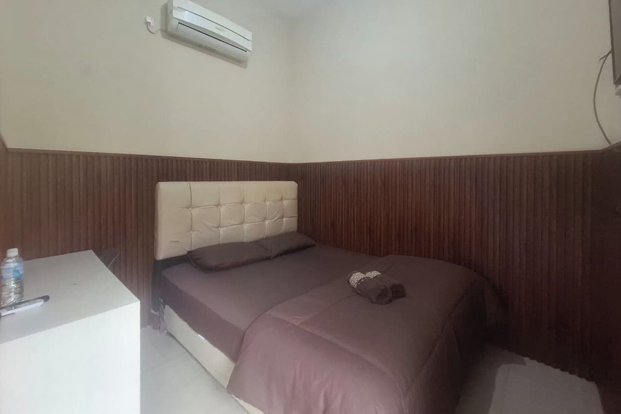 A bedroom with a bed, a bedside table, and an air conditioning unit.
