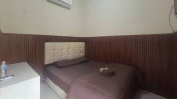 A bedroom with a bed, a bedside table, and an air conditioning unit.