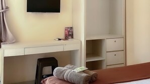 Une chambre d’hôtel comprenant un lit, un téléviseur fixé au mur, un bureau avec une chaise et une armoire.