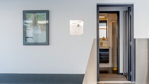 Un pasillo con un mapa en la pared, un lector de tarjetas de acceso y una escalera que lleva a otra habitación.