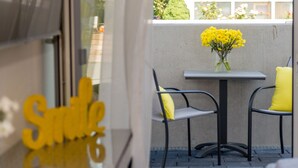 Un área de estar al aire libre con una mesa y sillas, un jarrón con flores amarillas y un letrero con la palabra "Smile".
