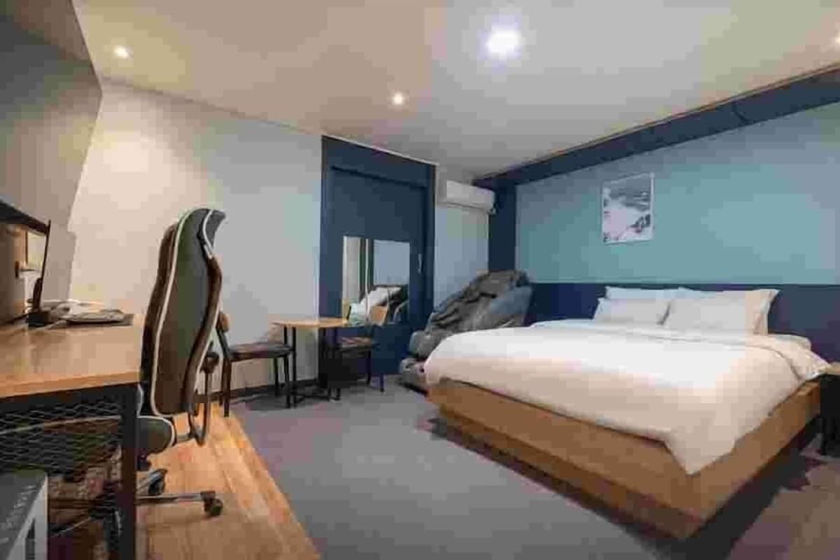 Ein modernes Hotelzimmer mit Bett, Schreibtisch, Stuhl und einem großen Spiegel.