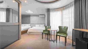 A hotel room with a bed, two chairs, a desk, and a TV. - CURVE HOTEL IKSAN (Iksan)