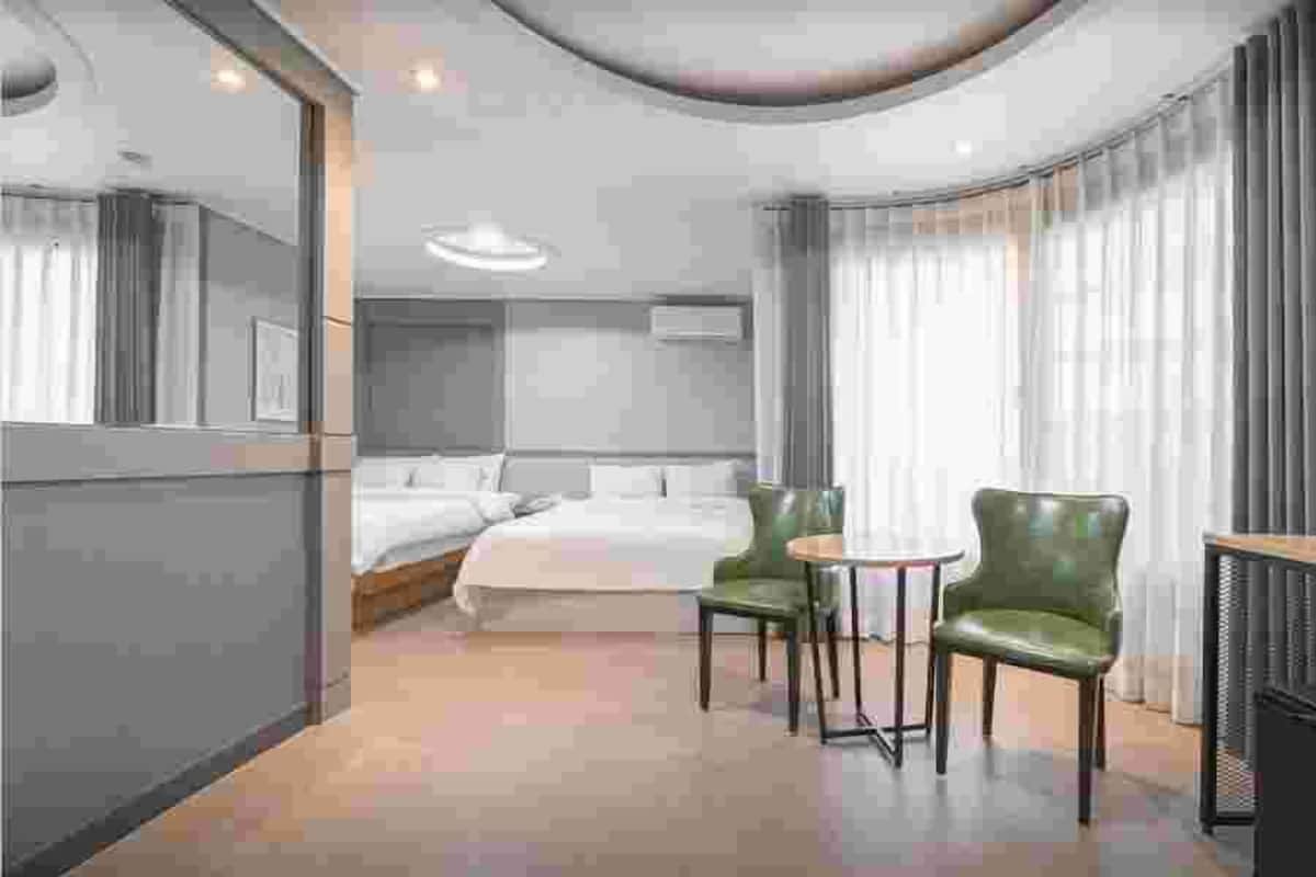 Ein Hotelzimmer mit einem Bett, zwei Sesseln, einem Schreibtisch und einem Fernseher.