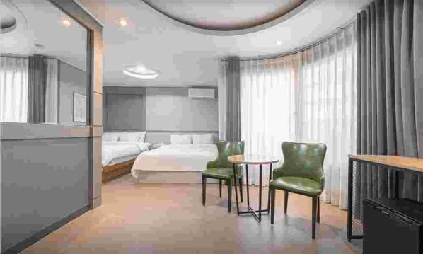 A hotel room with a bed, two chairs, a desk, and a TV. - CURVE HOTEL IKSAN (Iksan)