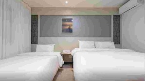 A hotel room with two beds, a small bedside table, and a window with a view. - CURVE HOTEL IKSAN (Iksan)