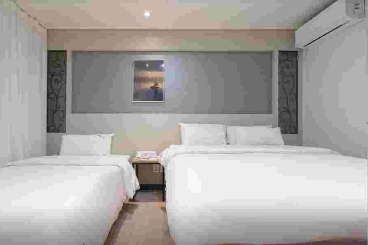 Ein Hotelzimmer mit zwei Betten, einem kleinen Nachttisch und einem Fenster mit Blick.