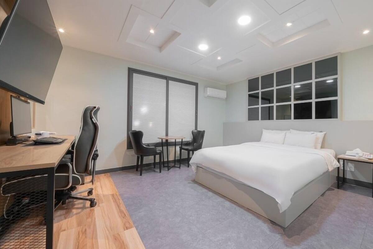 Ein modernes Hotelzimmer mit Bett, Schreibtisch, Stühlen und Fernseher.