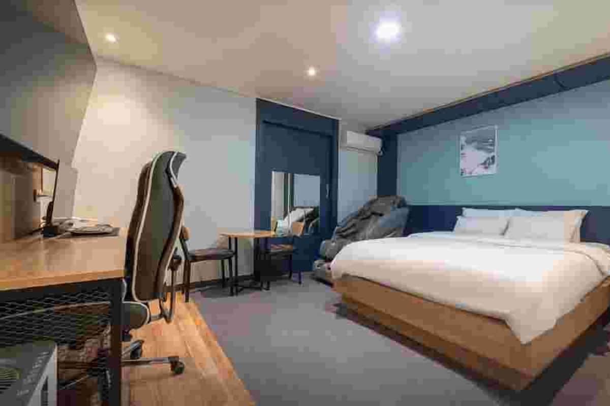 Ein modernes Hotelzimmer mit Bett, Schreibtisch, Stuhl und einem großen Fenster.