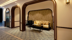 A hotel lobby with a patterned floor, a sofa with cushions, a coffee table, and a wall-mounted light fixture. - DAI NAM BOUTIQUE HOTEL (Ho Chi Minh City)