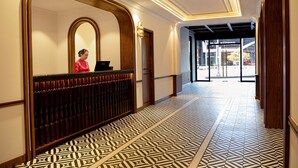 A hotel reception area with a patterned floor, a reception desk, and a large mirror. - DAI NAM BOUTIQUE HOTEL (Ho Chi Minh City)