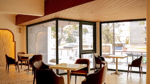 A modern interior with a high ceiling, large windows, and a mix of seating arrangements including tables and chairs. - DAI NAM BOUTIQUE HOTEL (Ho Chi Minh City)