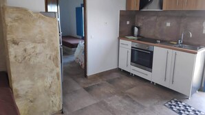 A compact kitchen with a refrigerator, oven, sink, and wooden cabinets. - Villa Aigli Anafi (Anafi)
