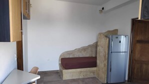 A compact kitchen with a built-in bench, a refrigerator, and a dining table. - Villa Aigli Anafi (Anafi)
