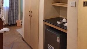 A room with a wardrobe, a small refrigerator, and a television mounted on the wall. - River Lumi Resort - Taveta (Chala)