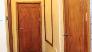 A wooden door with a brass handle and a keyhole, adjacent to a wall with a vertical wooden panel. - River Lumi Resort - Taveta (Chala)