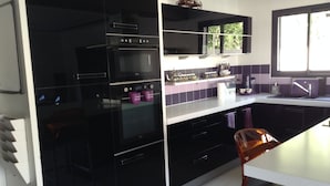 A modern kitchen with black cabinets, a built-in oven, and a window providing natural light. - LUXURY VILLA / SWIMMING POOL / SPA / 600m FROM THE BEACH / 12 GUESTS (Agde)