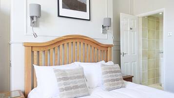 A neatly made bed with a wooden headboard, two bedside lamps, and a framed picture on the wall.