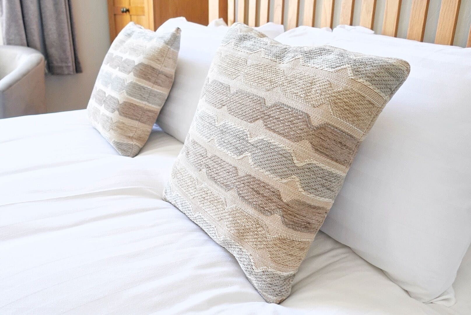 Two pillows on a bed with a wooden headboard.