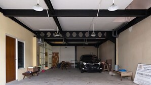 A covered parking area with a car, a signboard, and some construction materials. - Graha Asri Syariah (Sidoarjo)