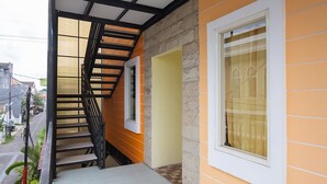 A staircase leading to a door with a window, a stone wall, and a view of the street. - Graha Asri Syariah (Sidoarjo)