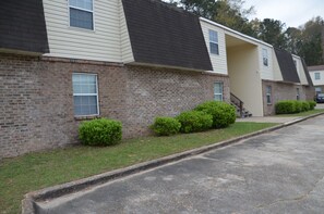 A row of two-story townhouses with brick exteriors and dark roofs, featuring small front yards with trimmed bushes. - Trendy Escape (Enterprise)