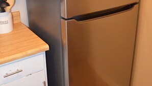 Ein Edelstahl-Kühlschrank in einer Küche mit weißen Schränken und einer Holz Arbeitsplatte.
