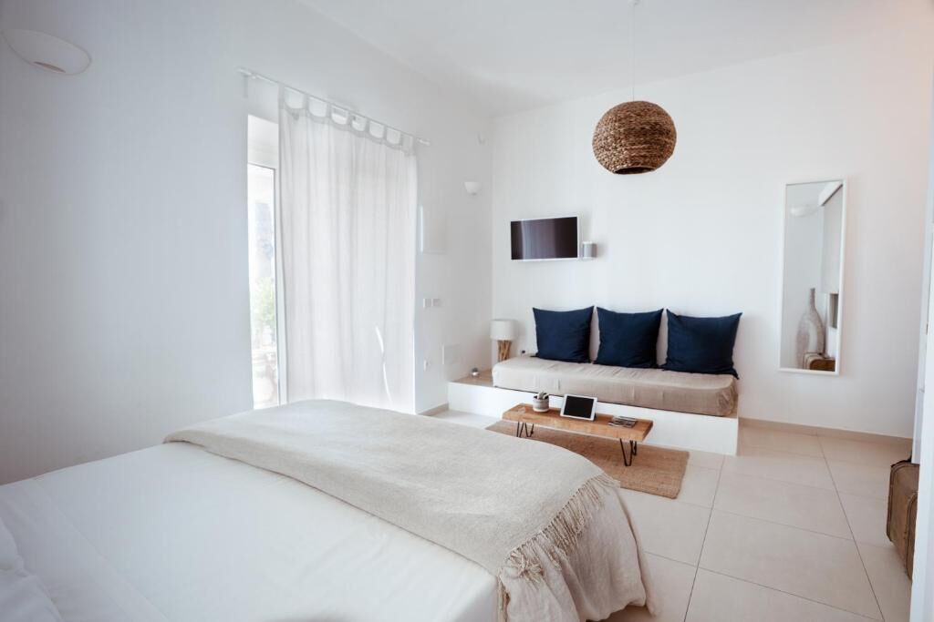 Un dormitorio moderno con una cama grande, un sofá, un televisor y un espejo.