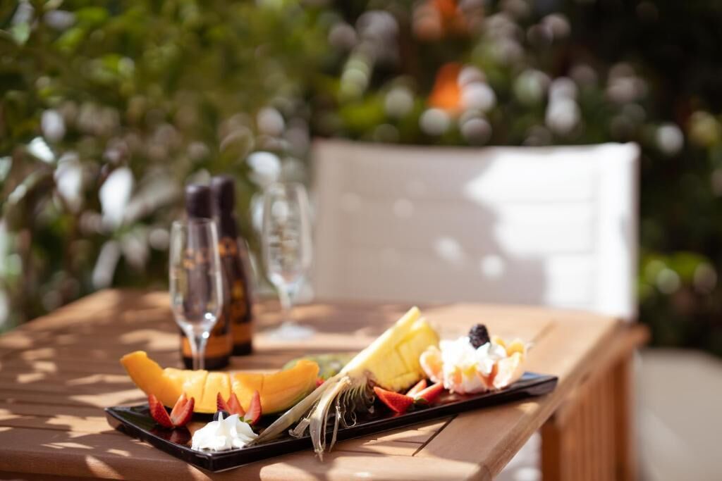 Una mesa con una bandeja de frutas, una botella y una copa.