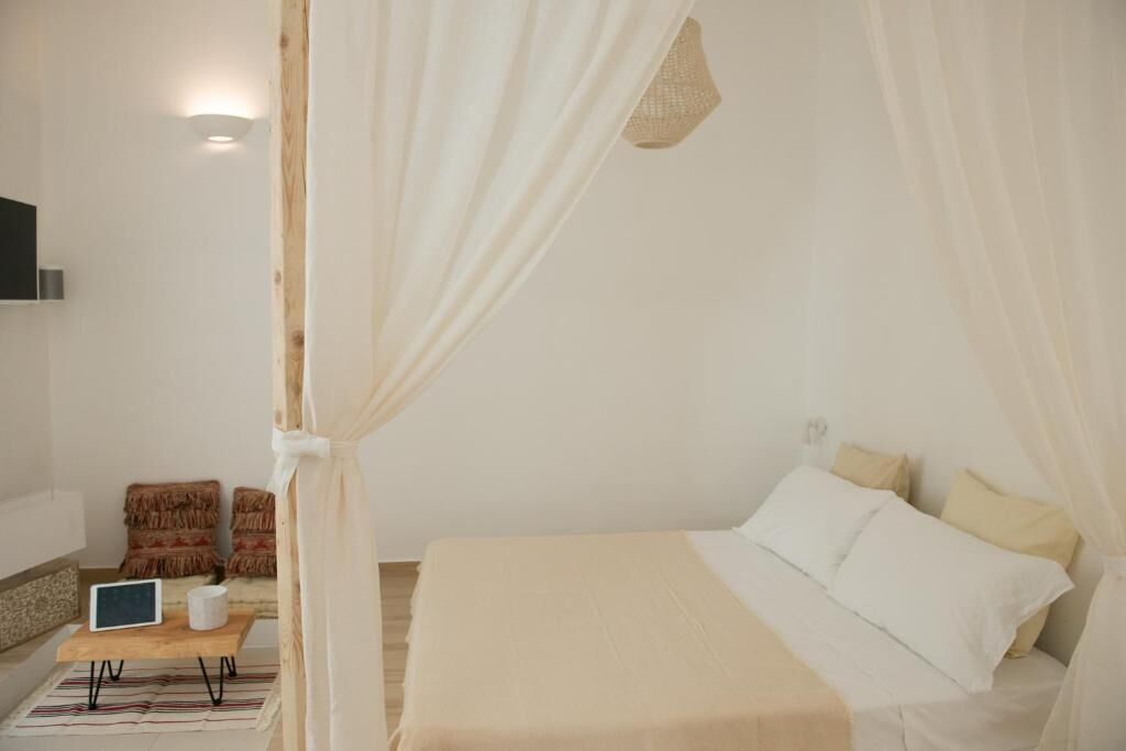 A bedroom with a bed, a bedside table, a lamp, and a chair.